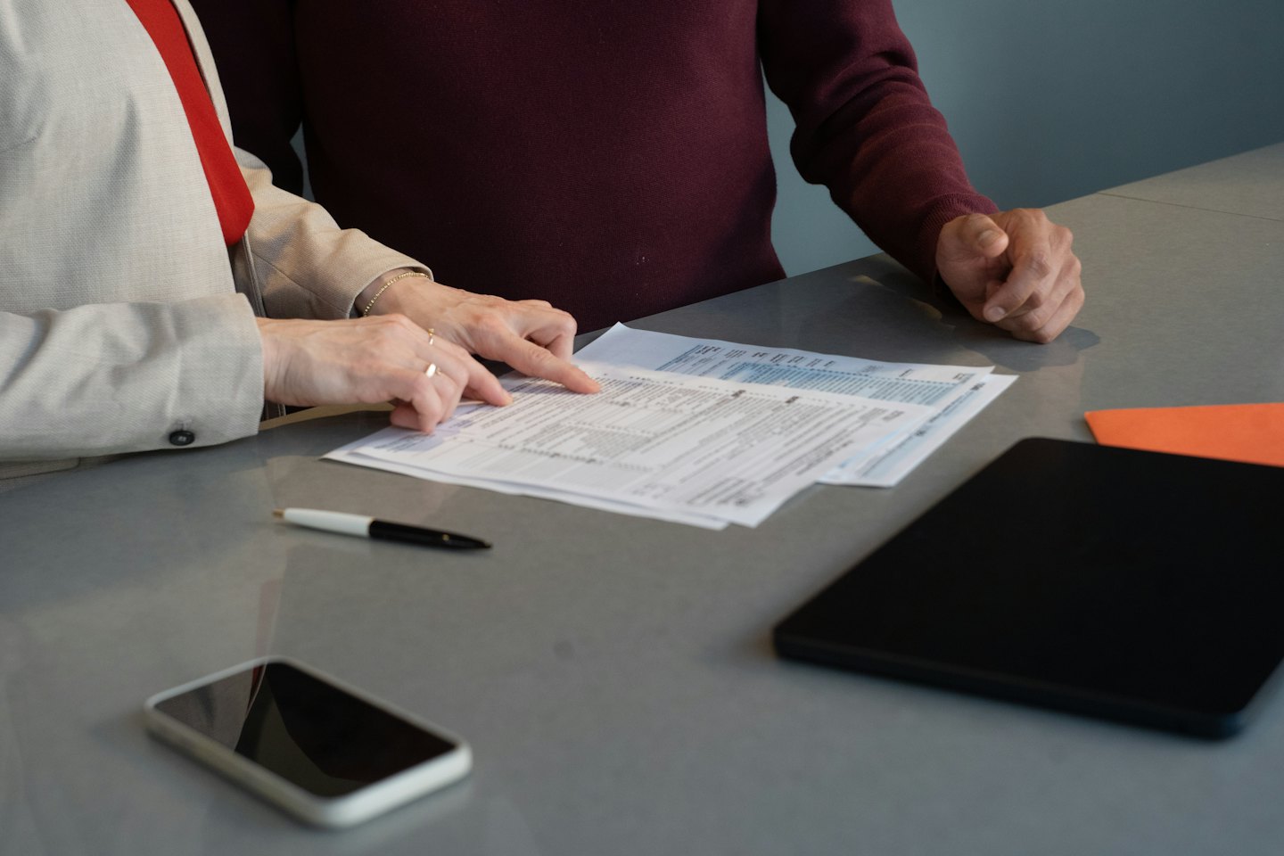 Two people reviewing financial documents at a desk.